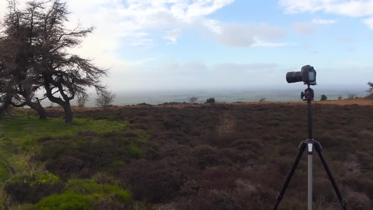 Adam setting up tripod on the moorland with dramatic sky