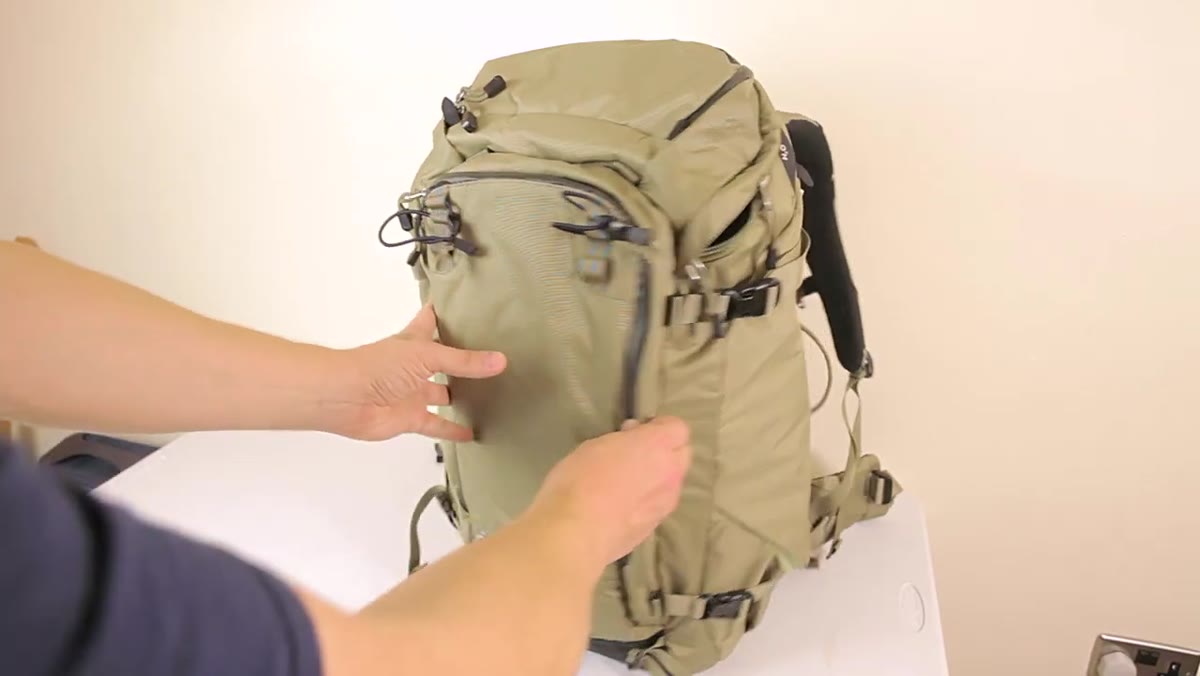 Adam sliding travel tripod into side pocket of the Sukha