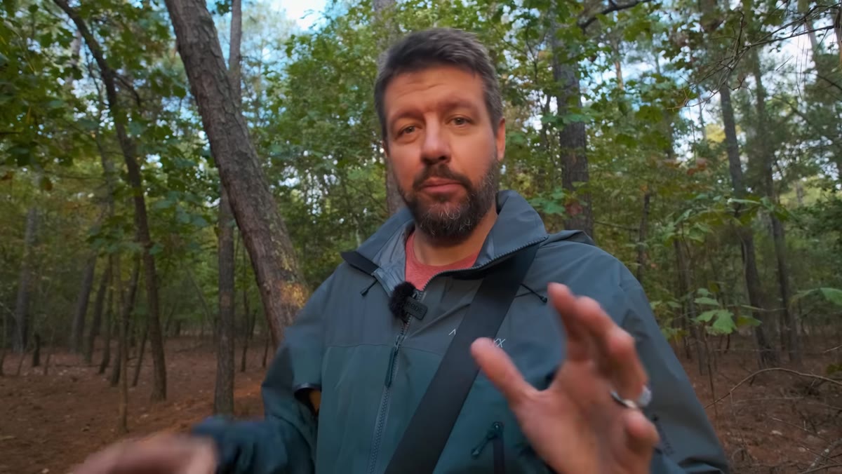 Mark walking slowly through woodland, pausing to raise camera repeatedly