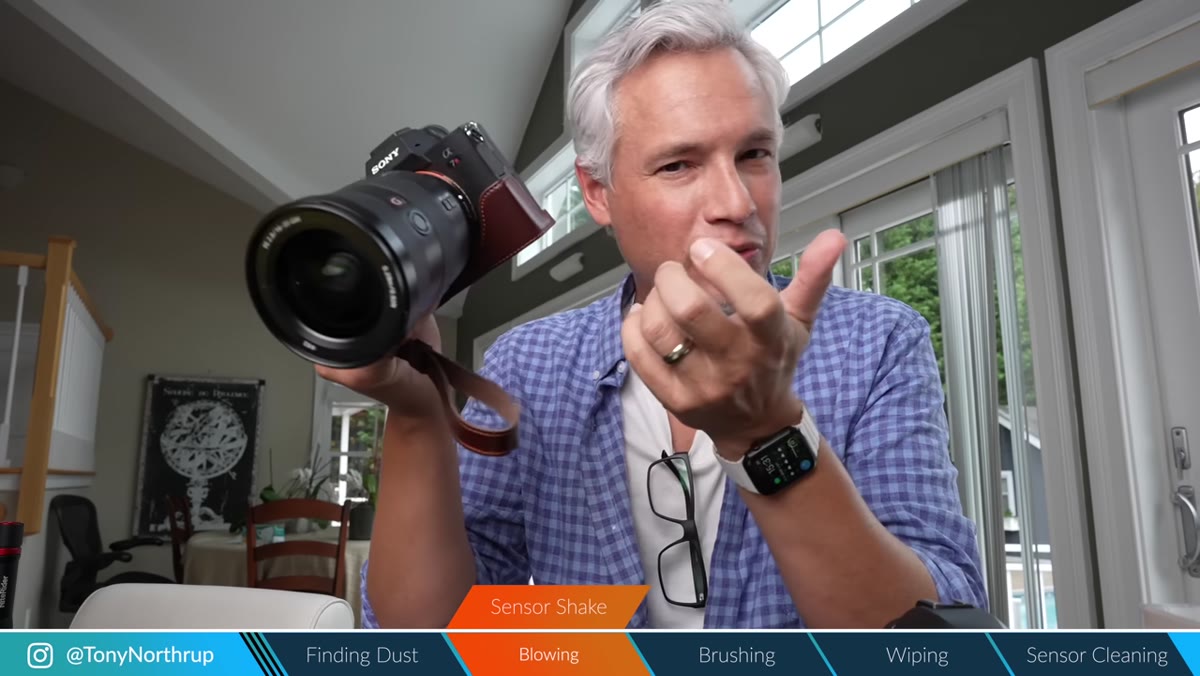 Camera held upside down with lens removed over table