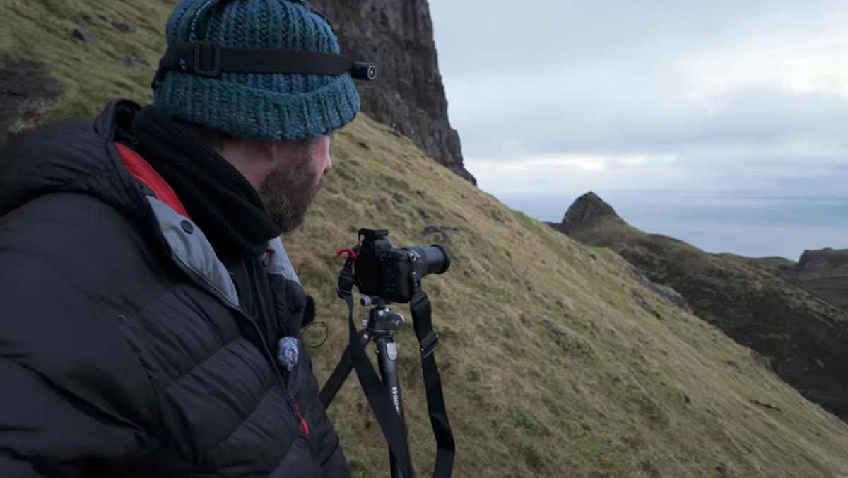 Danson explaining the stitching technique while gesturing at landscape