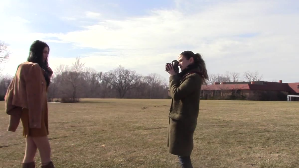 Model standing in field, photographer framing first shots