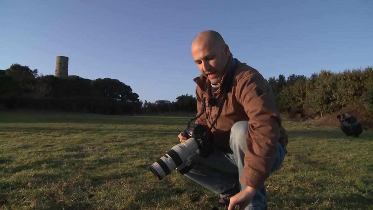 Photographer holding lens without hood attached outdoors