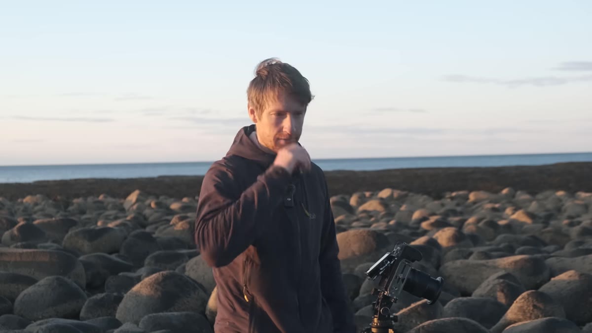 Thomas micro-adjusting camera position over the boulder foreground