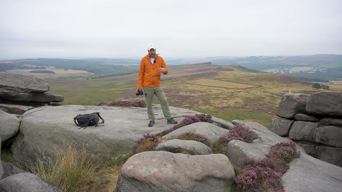 Danson explaining full-frame benefits while walking in heather field