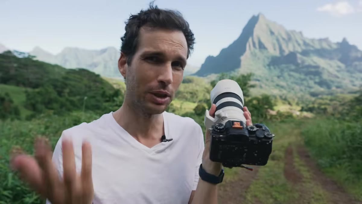 Host holding compact 70-200 f/4 lens next to camera