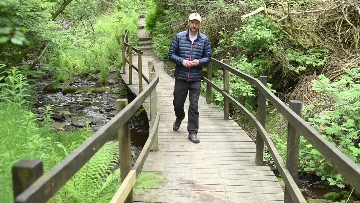Nigel walking through valley with camera, selecting lens