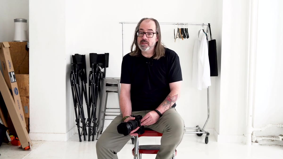 Daniel holding zoom lens, explaining outdated lens advice